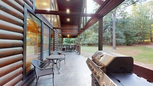 An outdoor patio with a grill, metal chairs, and tables.