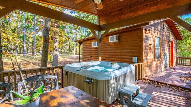 Una cabaña de madera con jacuzzi, terraza y mobiliario de jardín.