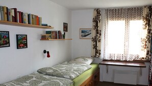 A small, tidy bedroom with a single bed, a desk, and a window with floral curtains. - Tgèsa Palits Seehuber by Interhome (Sedrun)