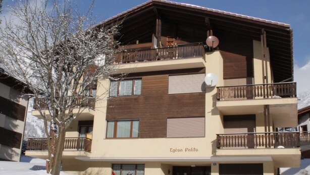 A multi-story building with balconies, a sign reading "Egésa Palits," and a snowy environment. - Tgèsa Palits Seehuber by Interhome (Sedrun)