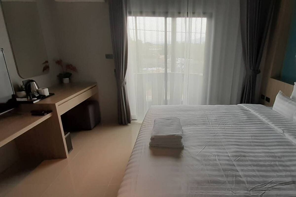 Ein Hotelzimmer mit Bett, Schreibtisch, Fernseher und einem Gemälde an der Wand.