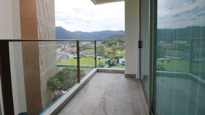 Un balcón con vistas a un parque verde y edificios a lo lejos.