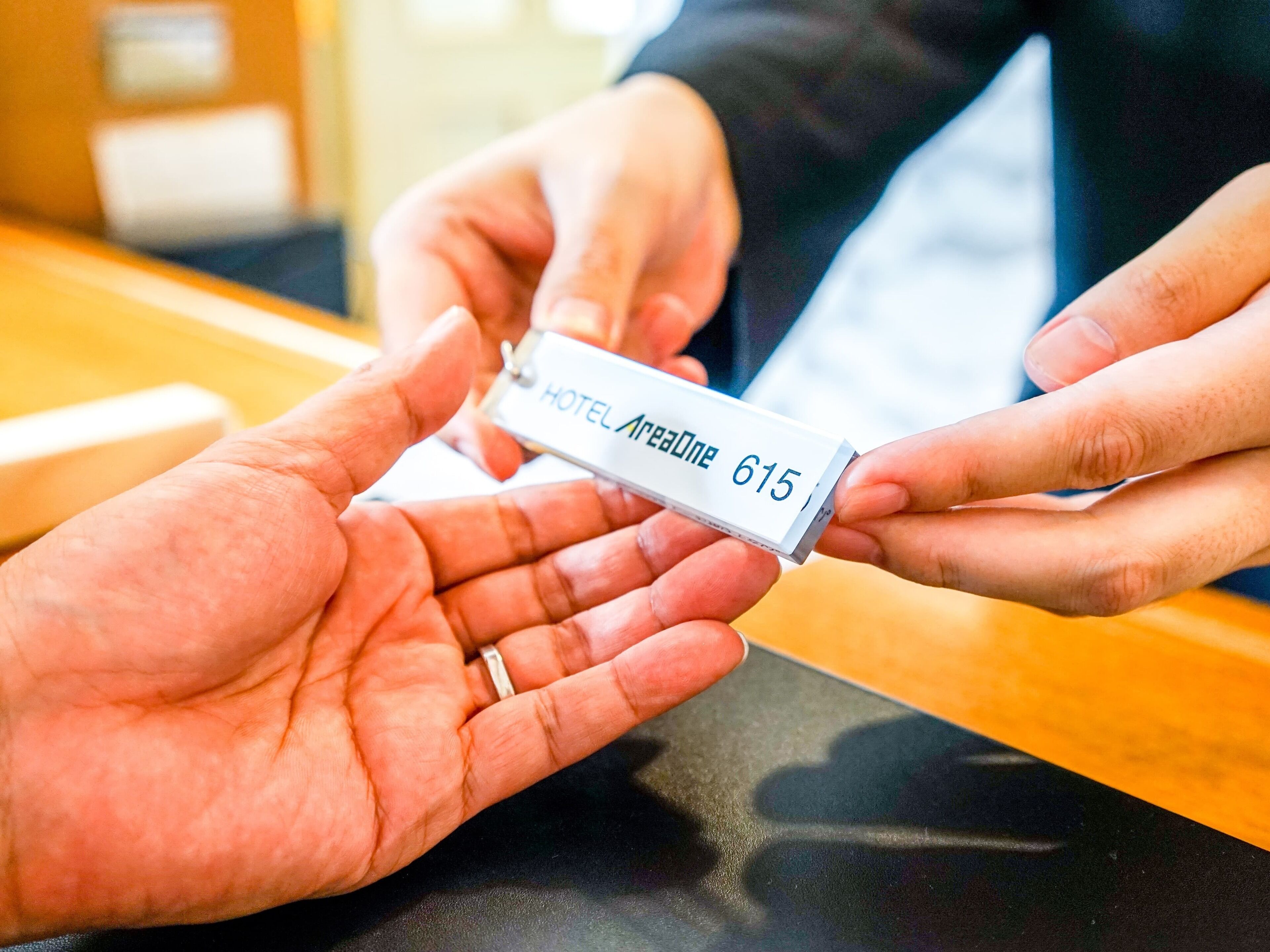A hand holding a hotel room keycard with the name "HOTEL Aresone 615".