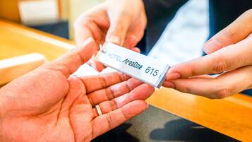 A hand holding a hotel room keycard with the name "HOTEL Aresone 615".