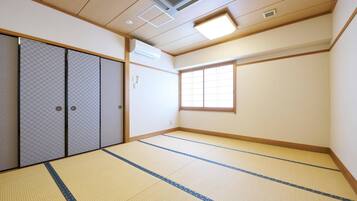 Una habitación japonesa tradicional con suelo de tatami, puertas correderas y un ventanal grande.