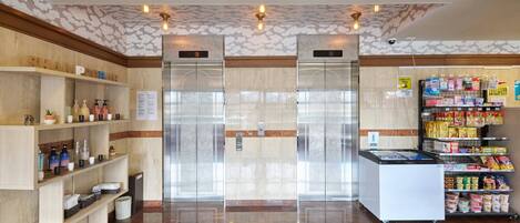 Eine saubere, gut beleuchtete Lobby mit einer Rezeption, einem Verkaufsautomaten und der Beschilderung für eine Toilette.