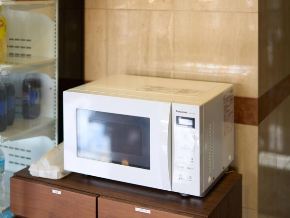 Un horno microondas Panasonic blanco sobre un mueble de madera en una cocina.