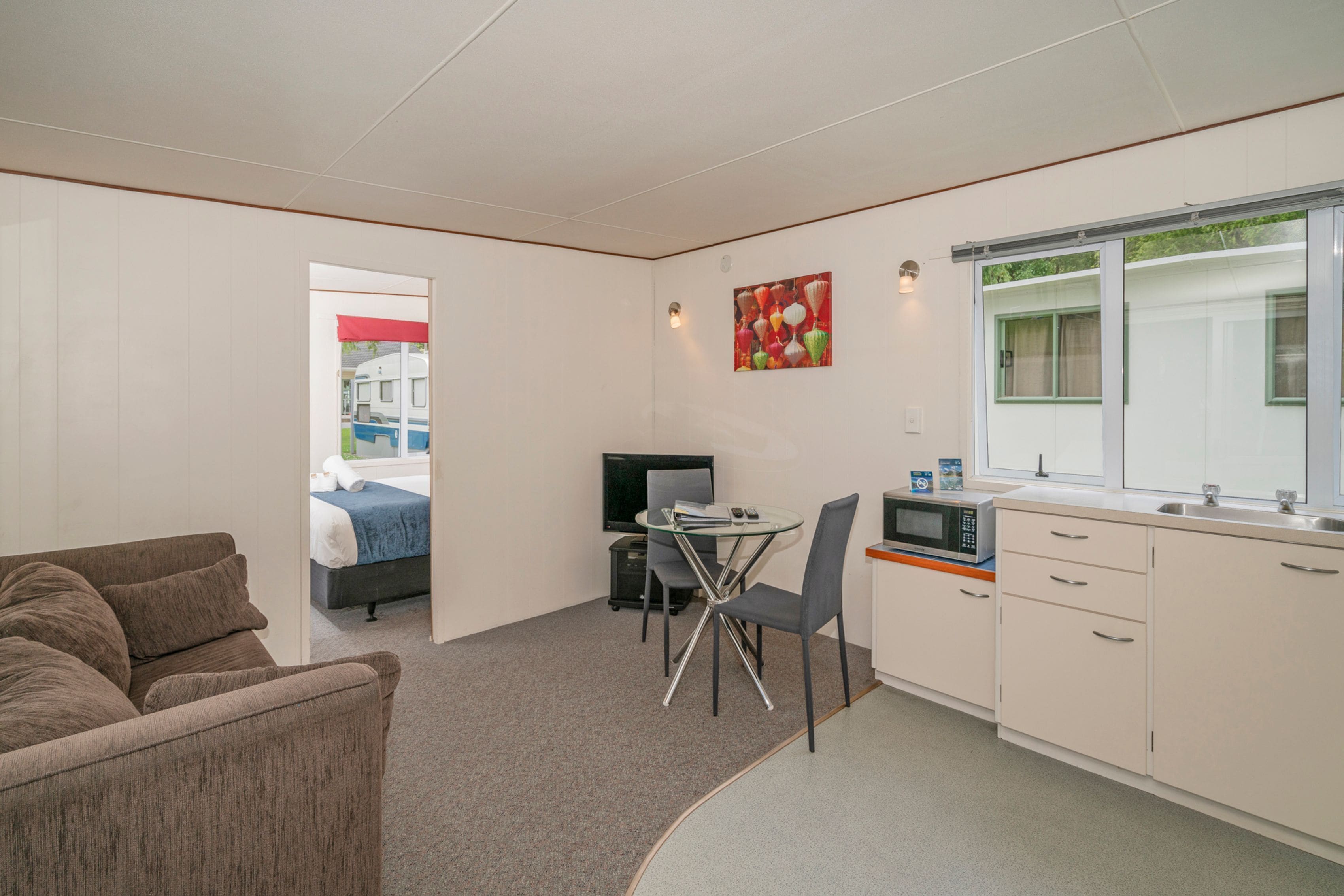 A compact room with a kitchenette, a dining area, and a bed.