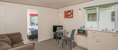 A compact room with a kitchenette, a dining area, and a bed.