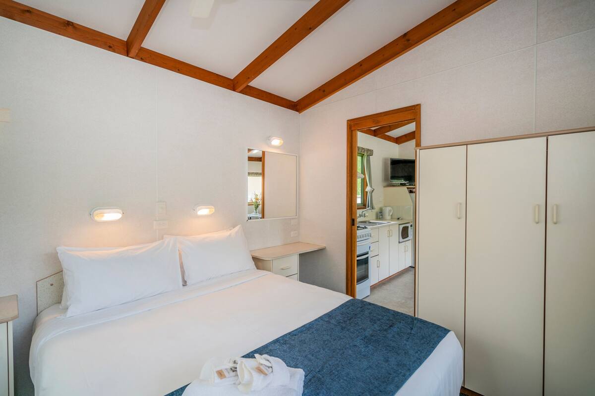Un dormitorio con cama, mesitas de noche, un espejo y un armario.
