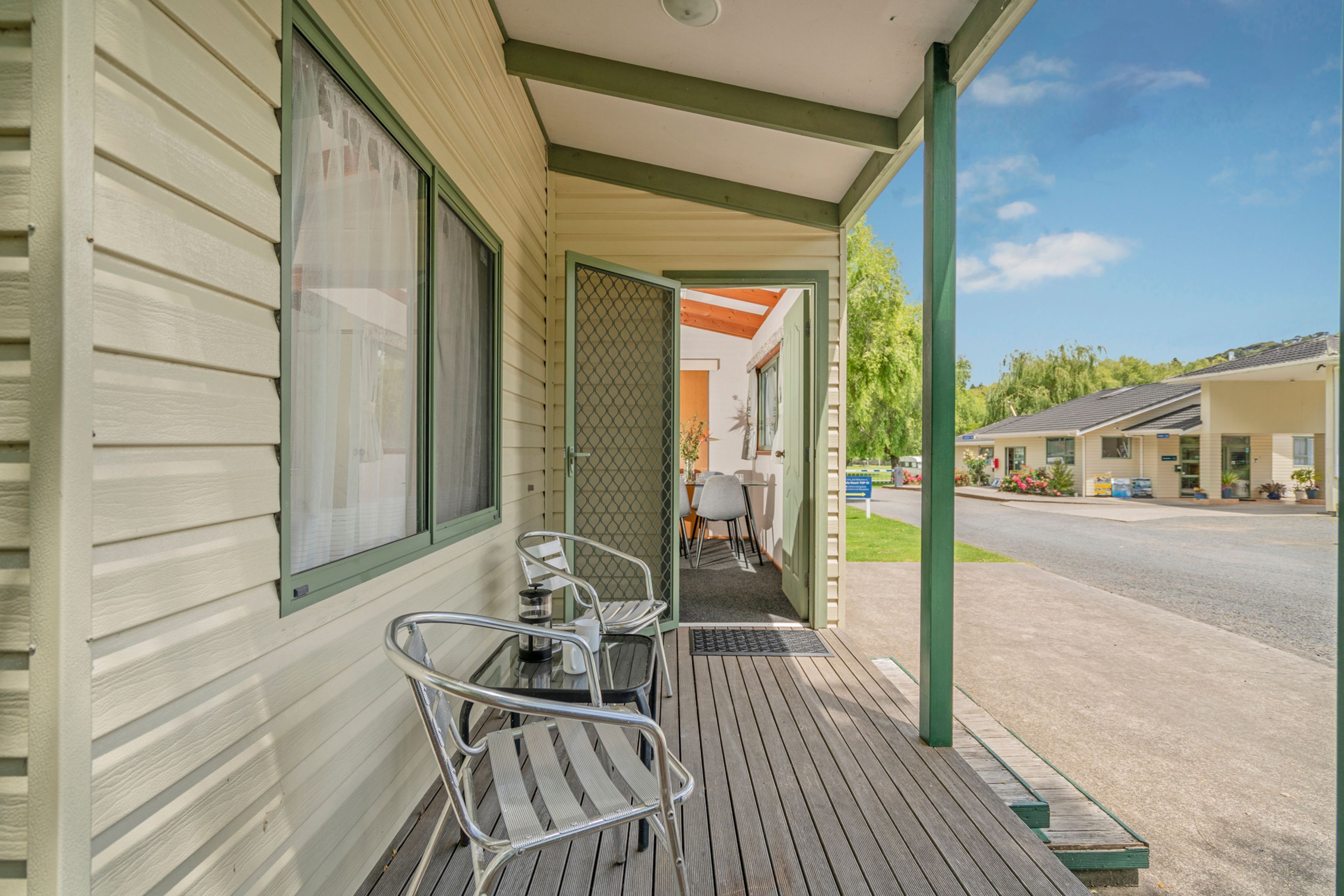 A motel with a covered porch, a table with chairs, and a view of the street.