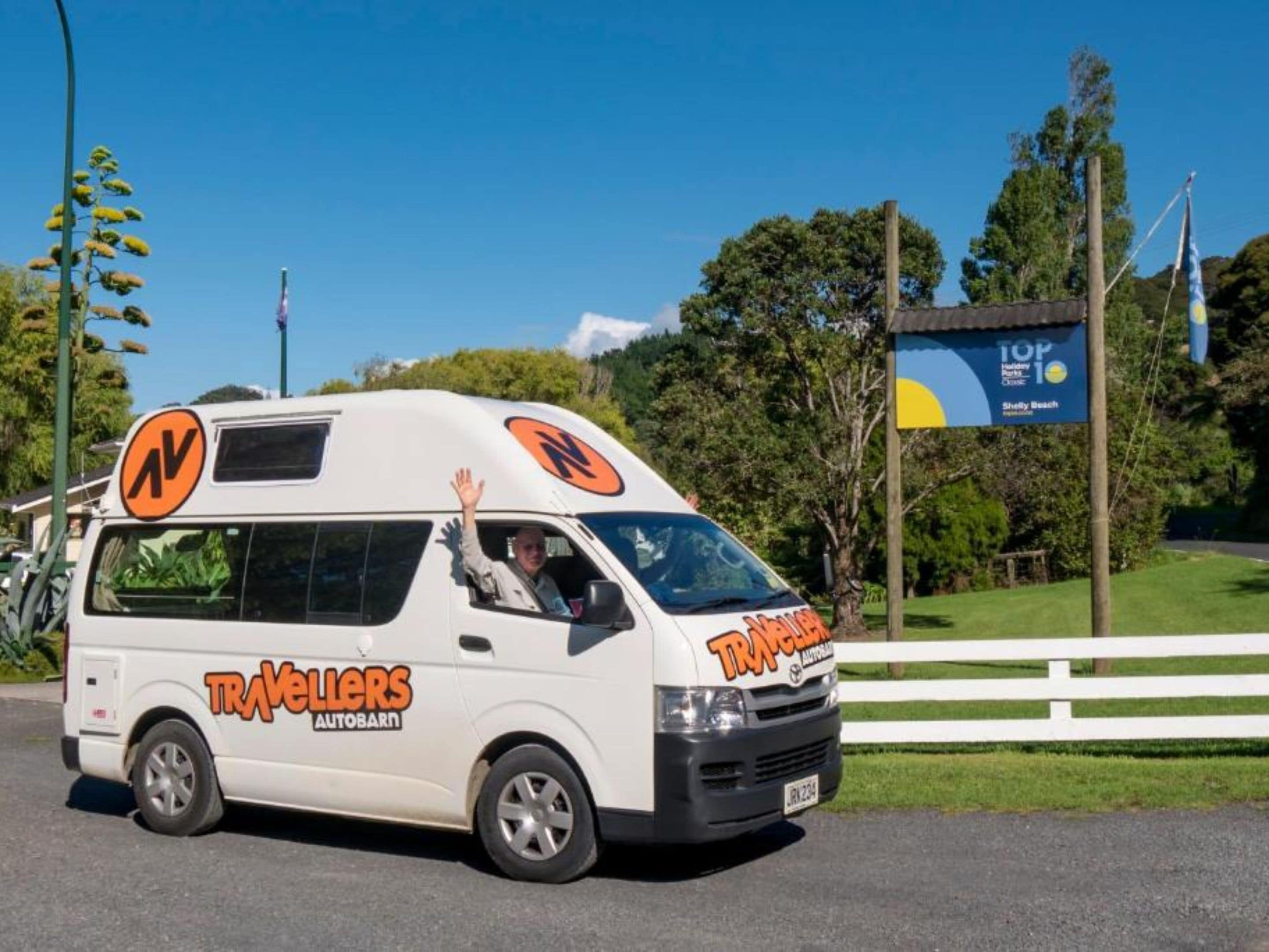 A white van with 'Travelers Auto Barn' branding parked on a road.