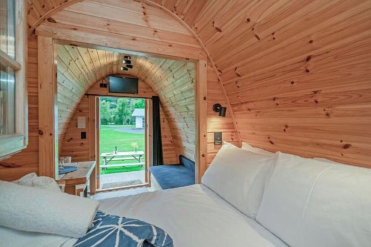 Una habitación de cabaña de madera acogedora, con una cama, una mesita pequeña y un banco.