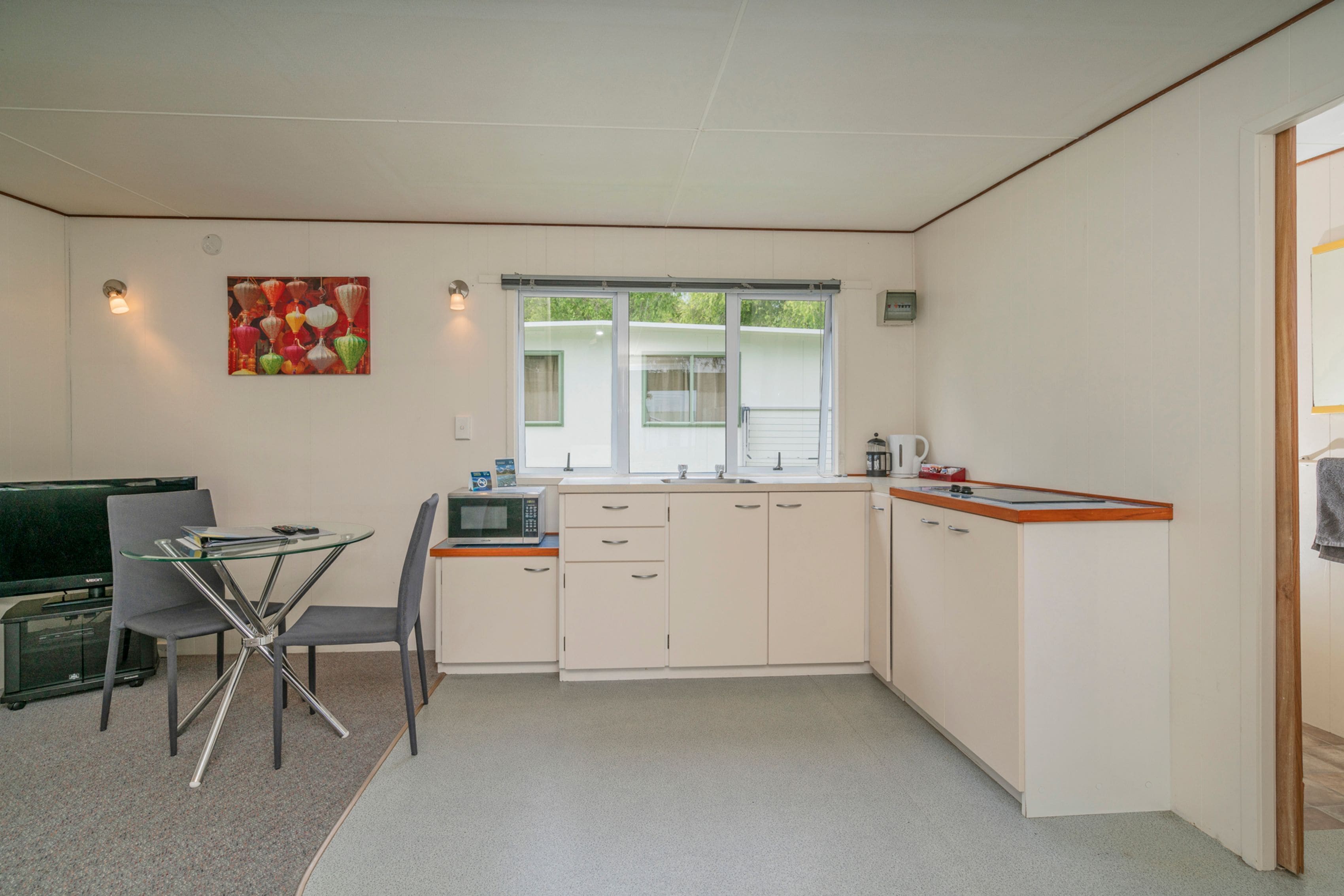 A compact kitchen with a dining area, featuring a microwave, sink, and a small table with chairs.