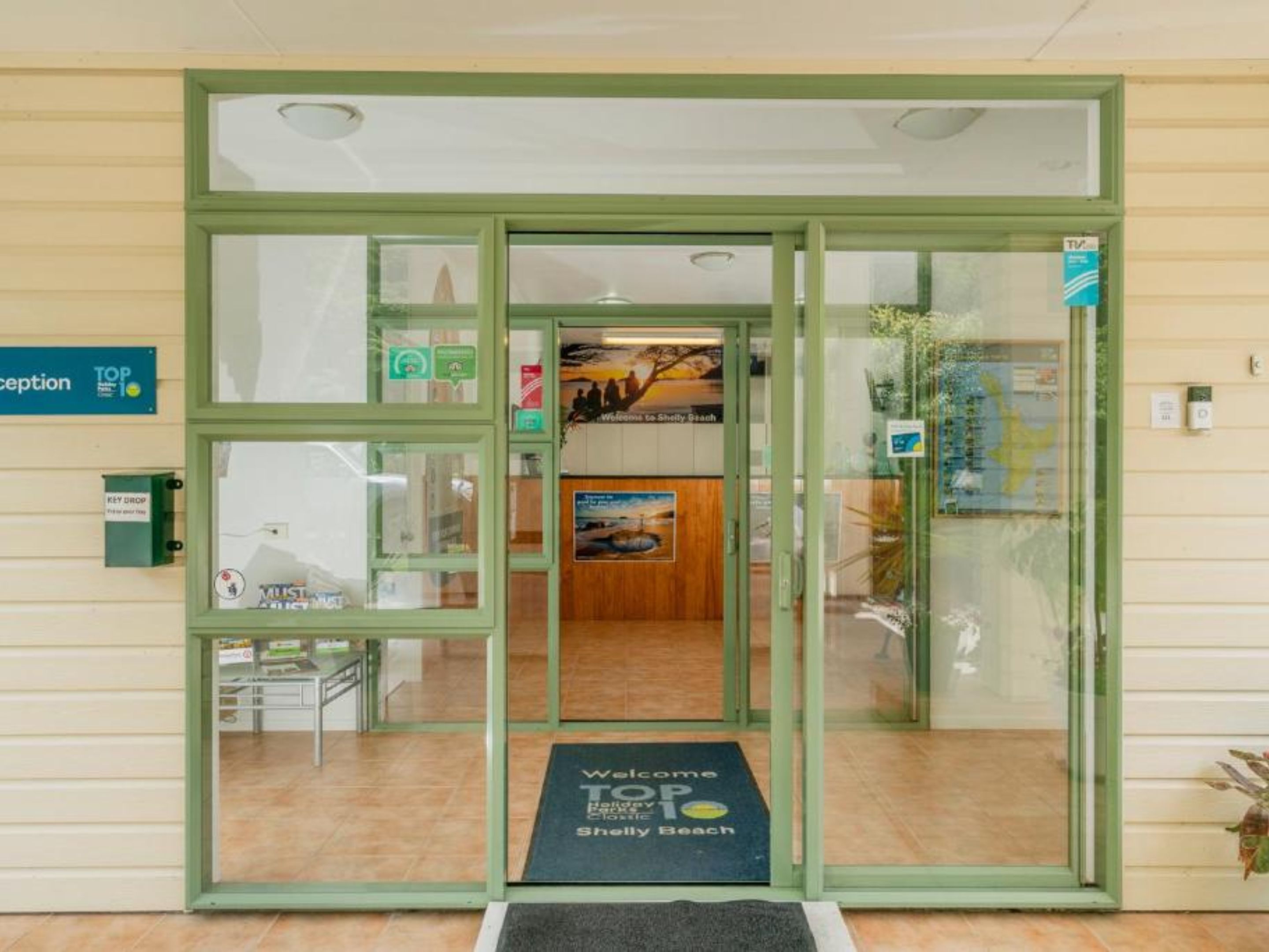 A reception area with a glass door, a welcome mat, and a sign indicating the reception.
