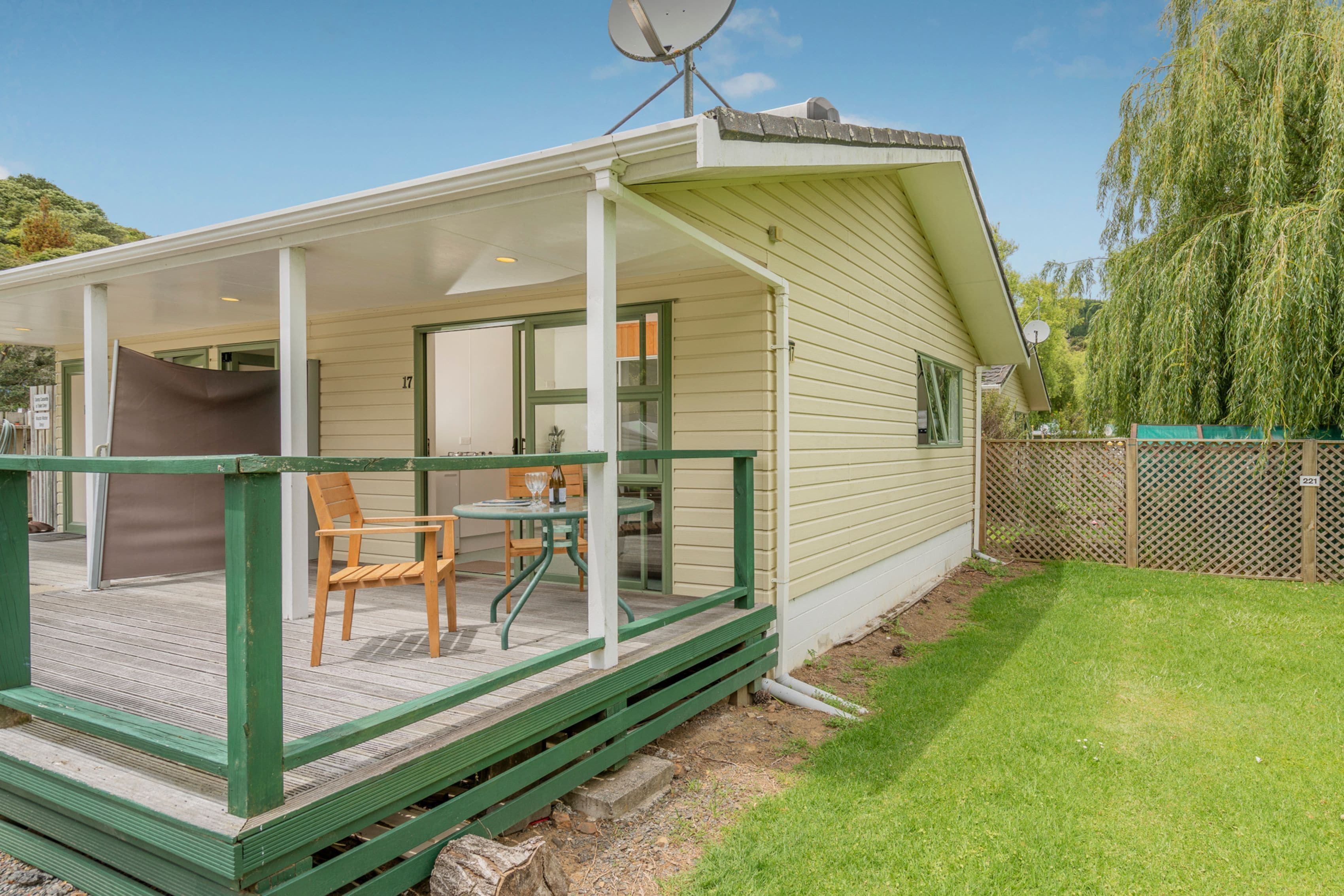 A single-story house with a covered porch, a satellite dish, and a fenced yard.