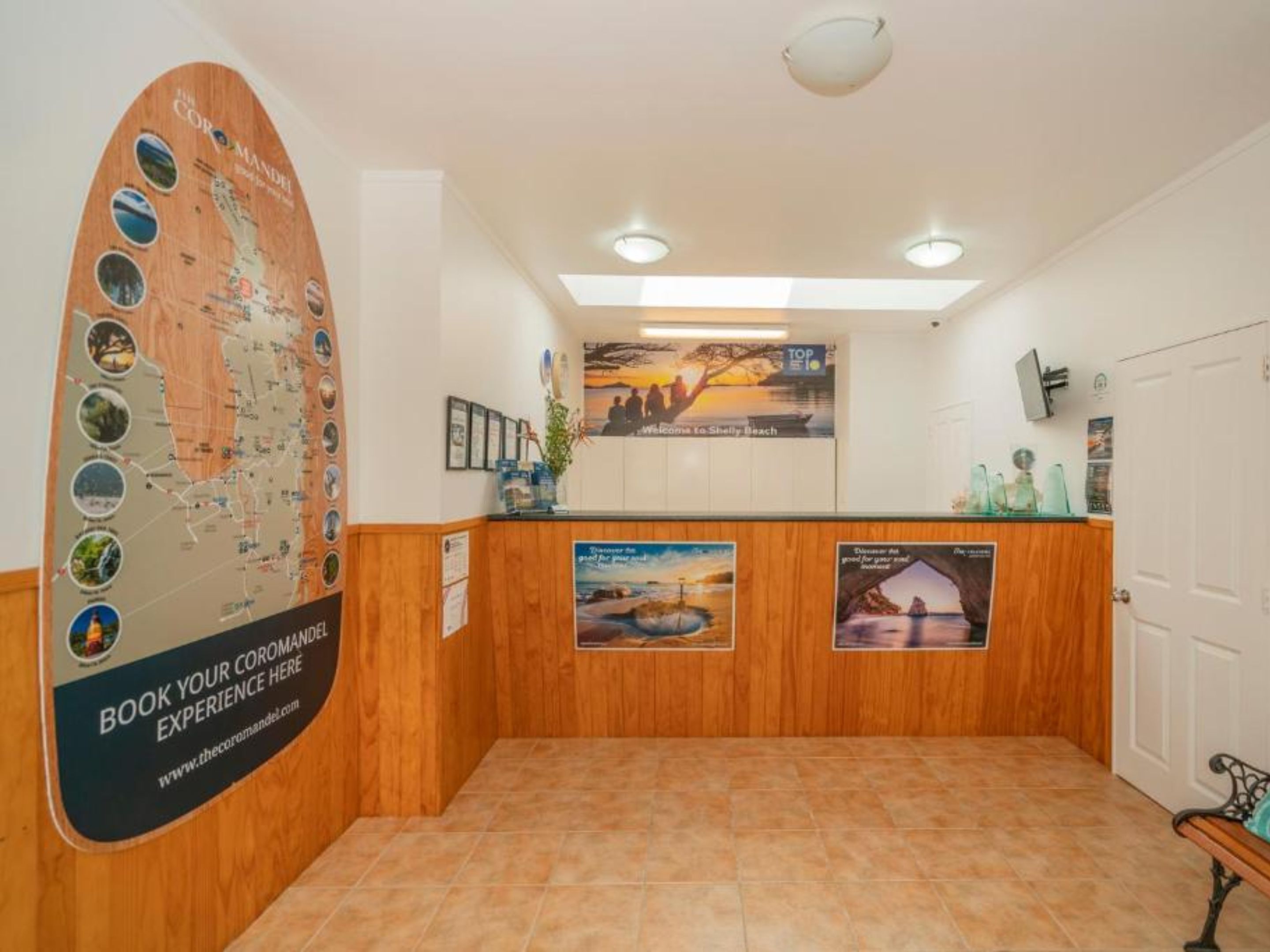 Ein Empfangsbereich mit einem Holzbüro, einer großen Karte an der Wand und einem Plakat, das Besucher am Shelly Beach willkommen heißt.