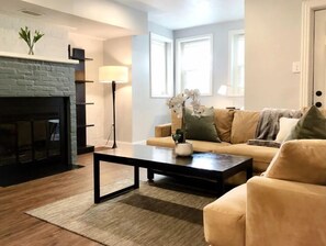 Cozy up by the fireplace in this stylish living room, featuring a comfortable sofa and a functional design.