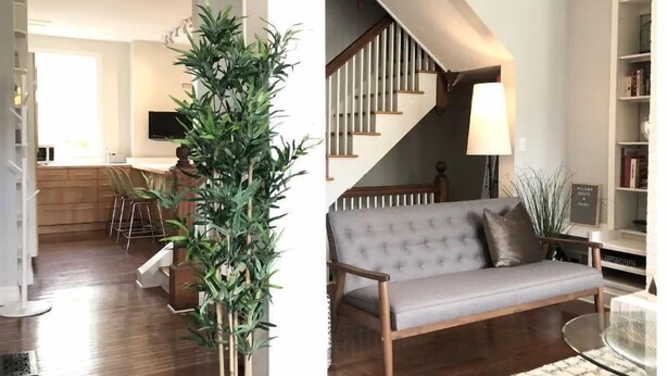 A modern living room with a grey sofa, a staircase, and a dining area with wooden furniture.