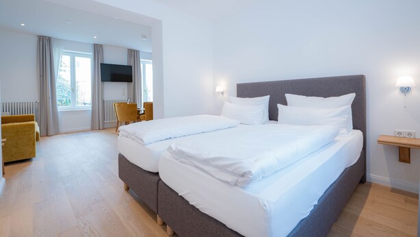 Une chambre d’hôtel moderne équipée d’un grand lit, d’un téléviseur à écran plat, d’un bureau et d’une chaise.