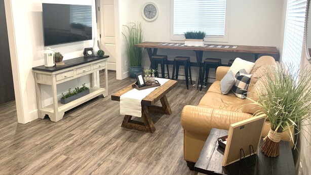 A living room with a TV, a coffee table, a sofa, and a dining area with a bar stool. - ★Home away from Home ★ (Tremonton)
