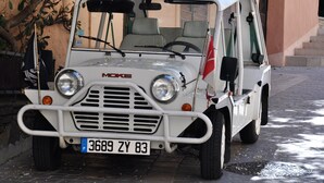 A white Moke vehicle parked on a cobblestone street.
