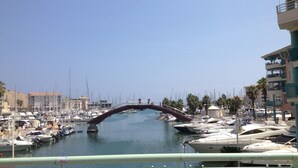 A marina with numerous boats docked, a pedestrian bridge, and buildings with balconies.