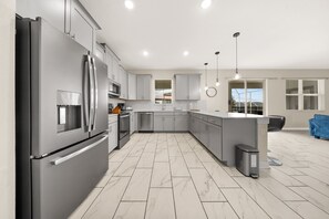 Une cuisine moderne dotée d’appareils électroménagers en acier inoxydable, de meubles de couleur grise et d’un grand îlot central.