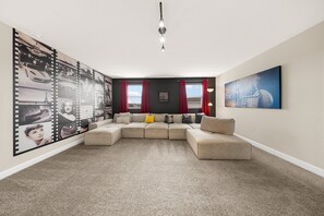 Ein Wohnzimmer mit einer Eckcouch, einem großen Filmplakat und einem Schild mit der Aufschrift 'Popcorn'.