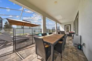 Eine Außenpatio mit Tisch und Stühlen, einem Pool und einem überdachten Bereich mit Sonnenschirm.