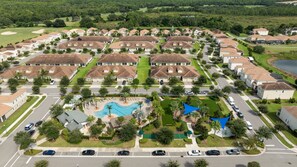 A residential area with houses, a swimming pool, and a golf course in the background.