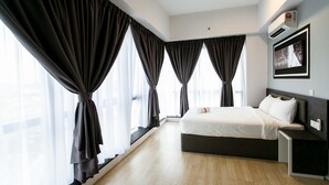 A modern hotel room with a large bed, a bedside table, a nightstand, and a window with curtains. - Aurora Pavilion Bukit Jalil by Ody Suites (Kuala Lumpur)