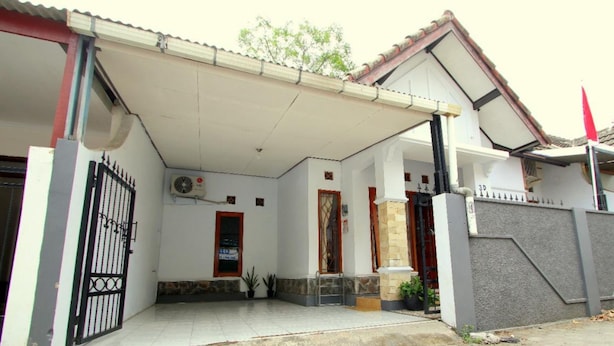 A residential building with a covered entrance, a gated driveway, and a tiled patio area.