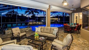 A poolside area with outdoor seating and a view of the pool at dusk.