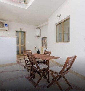A dining area with a wooden table and chairs, a tiled floor, and a window.
