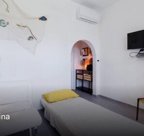 A modern bedroom with a bed, a sofa, a chair, and a TV.