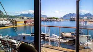 A view from a balcony overlooking a harbor with boats, colorful buildings, and mountains in the background. - Nordis Apartments (Vagan)