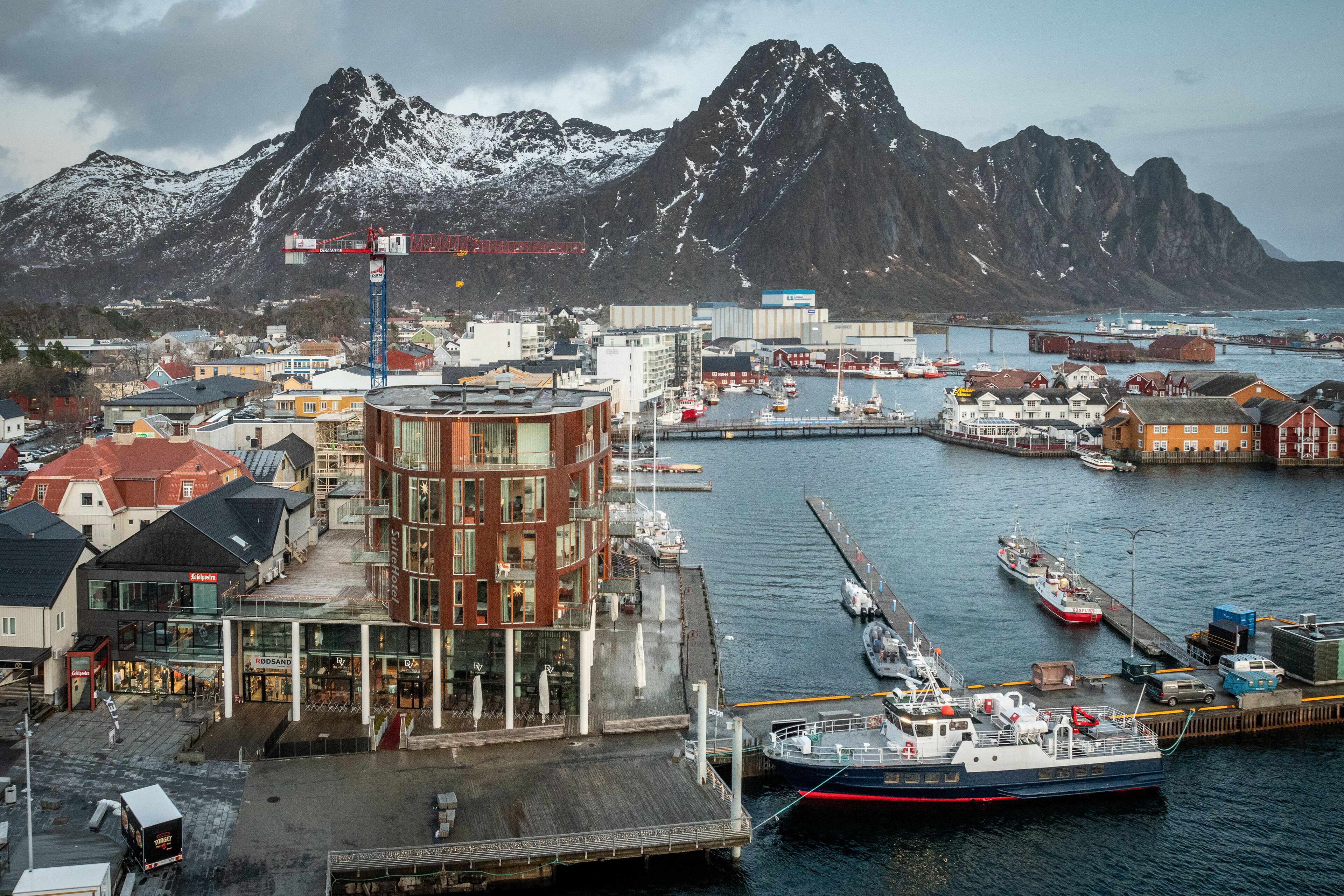 Ein Hafen mit Booten, einem Kran und Gebäuden mit Geschäften.