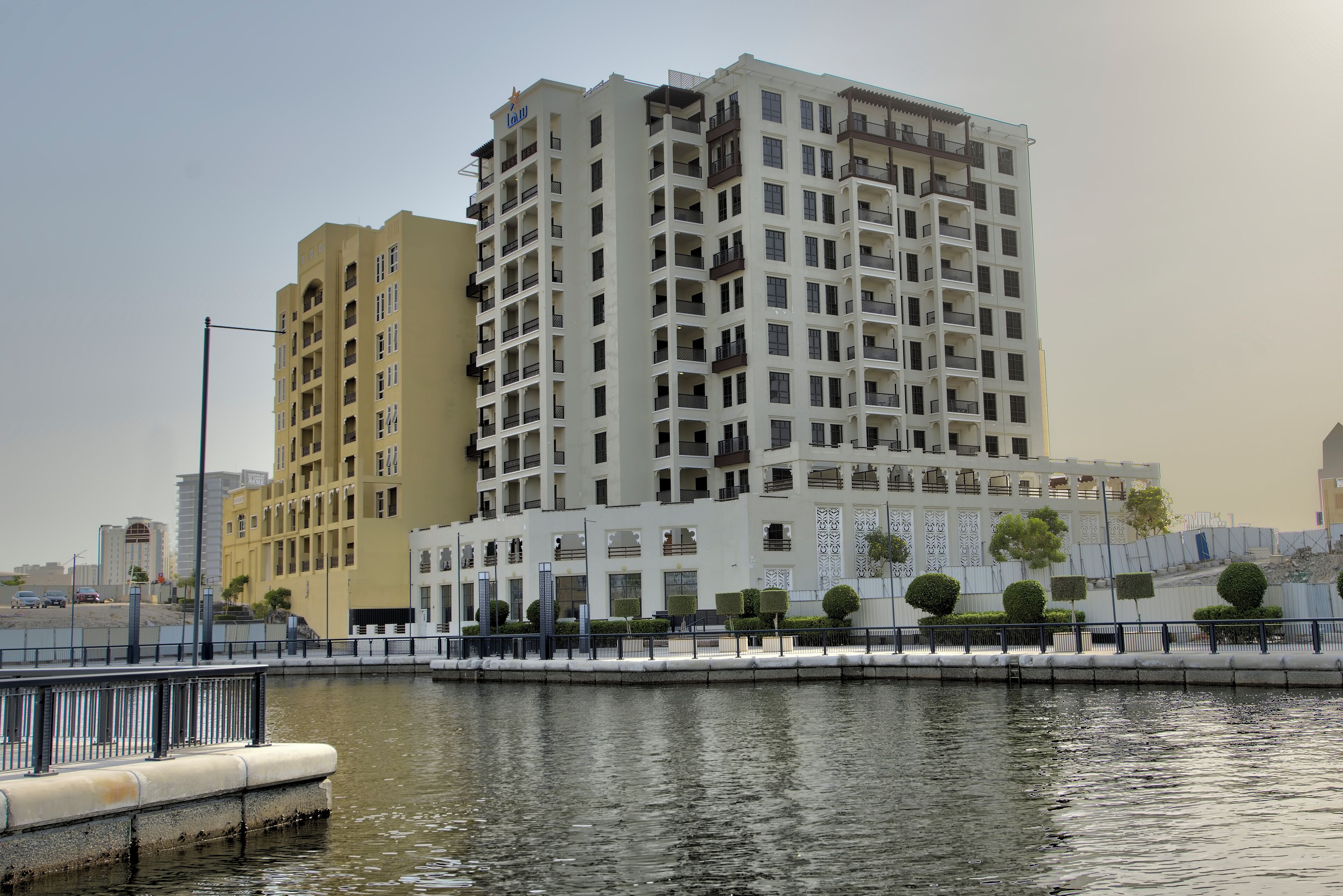A high-rise building with multiple balconies and a waterfront view.