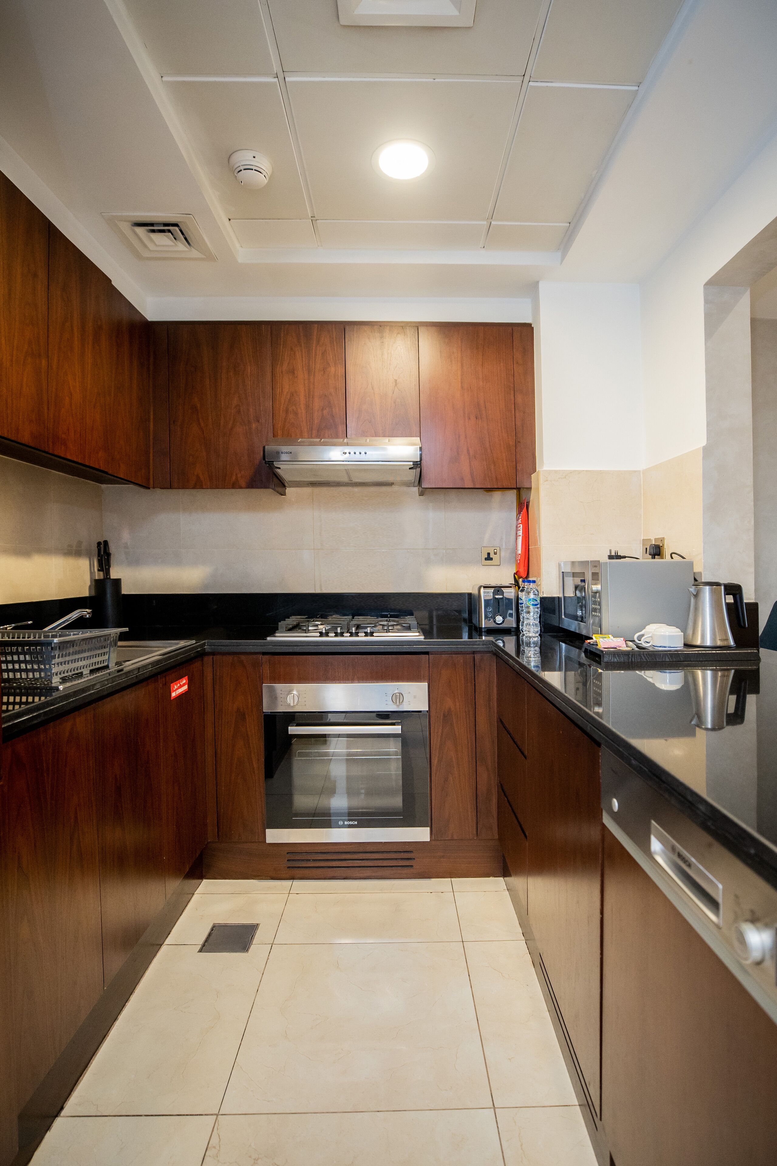 A modern kitchen with wooden cabinets, stainless steel appliances, and a black countertop.