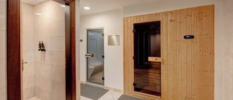 A hotel entrance with a wooden door, a glass shower room, and a tiled floor.