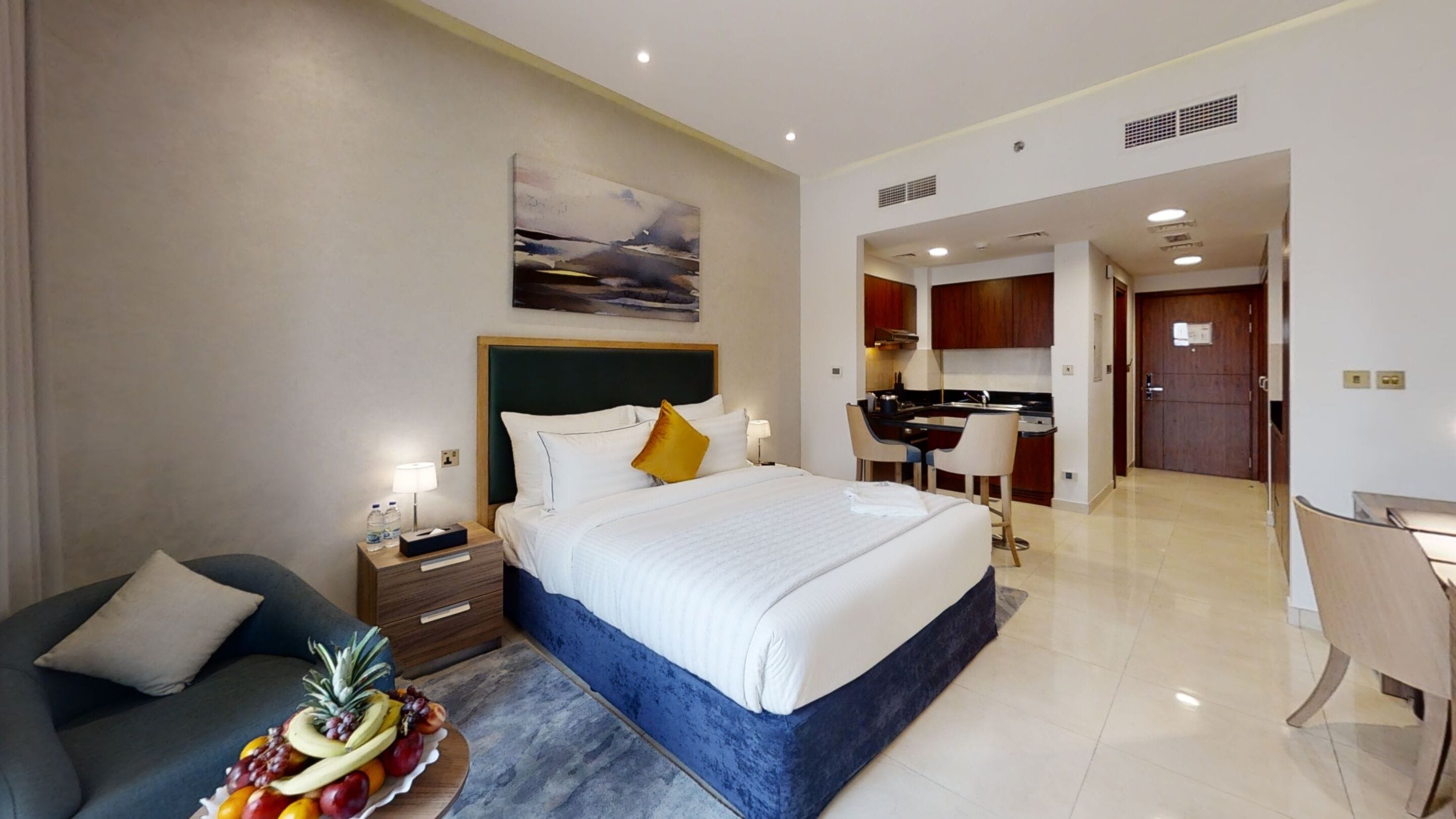 A hotel room with a bed, a desk, and a kitchenette.