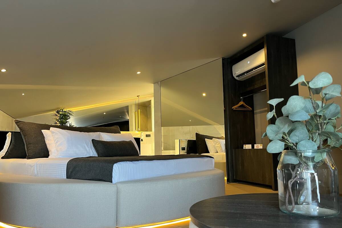Ein modernes Schlafzimmer mit Bett, Nachttisch und einer hängenden Pflanze.