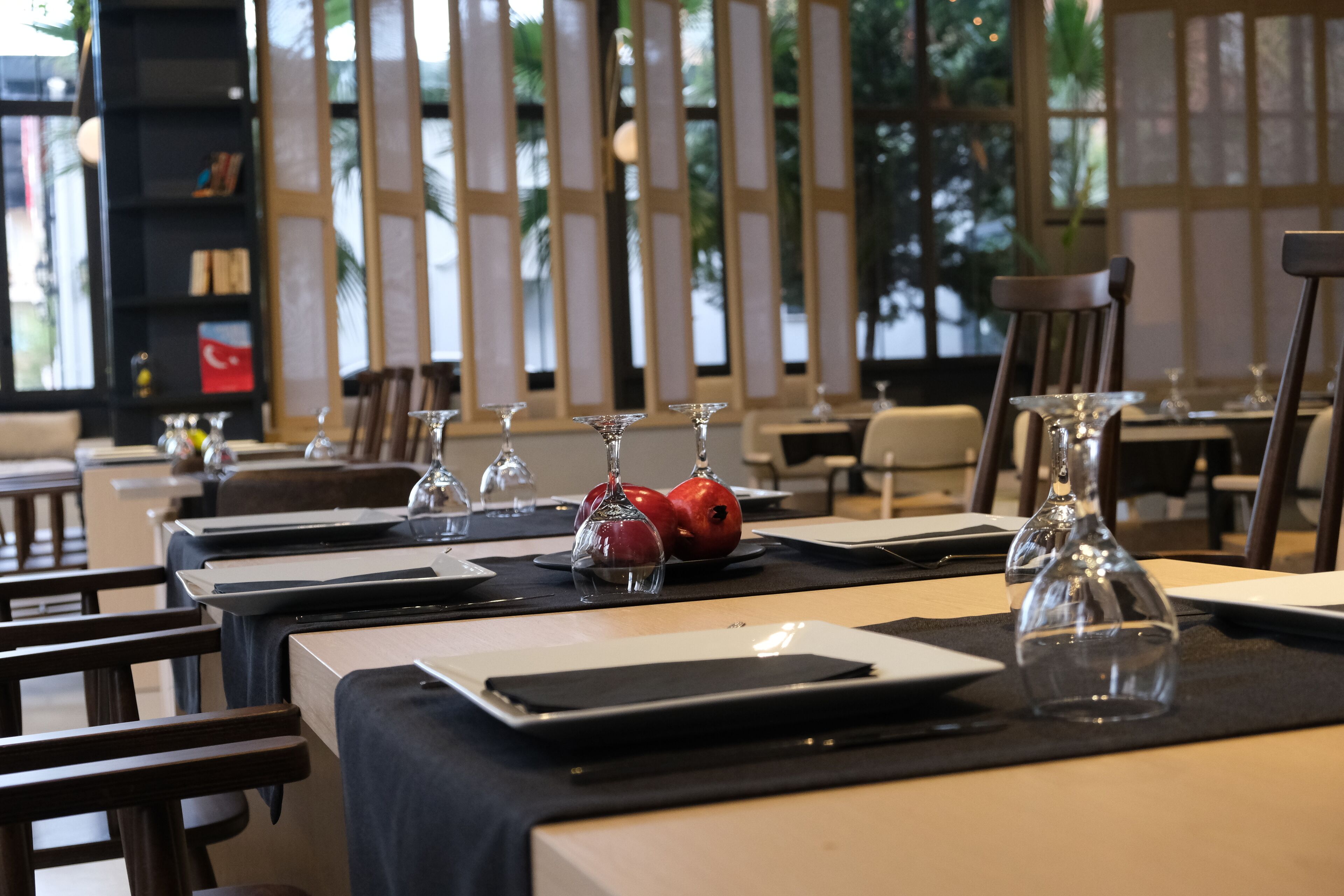 Un espace repas avec des tables dressées pour le service, agrémenté de beaux verres et d’une grenade sur chaque table.