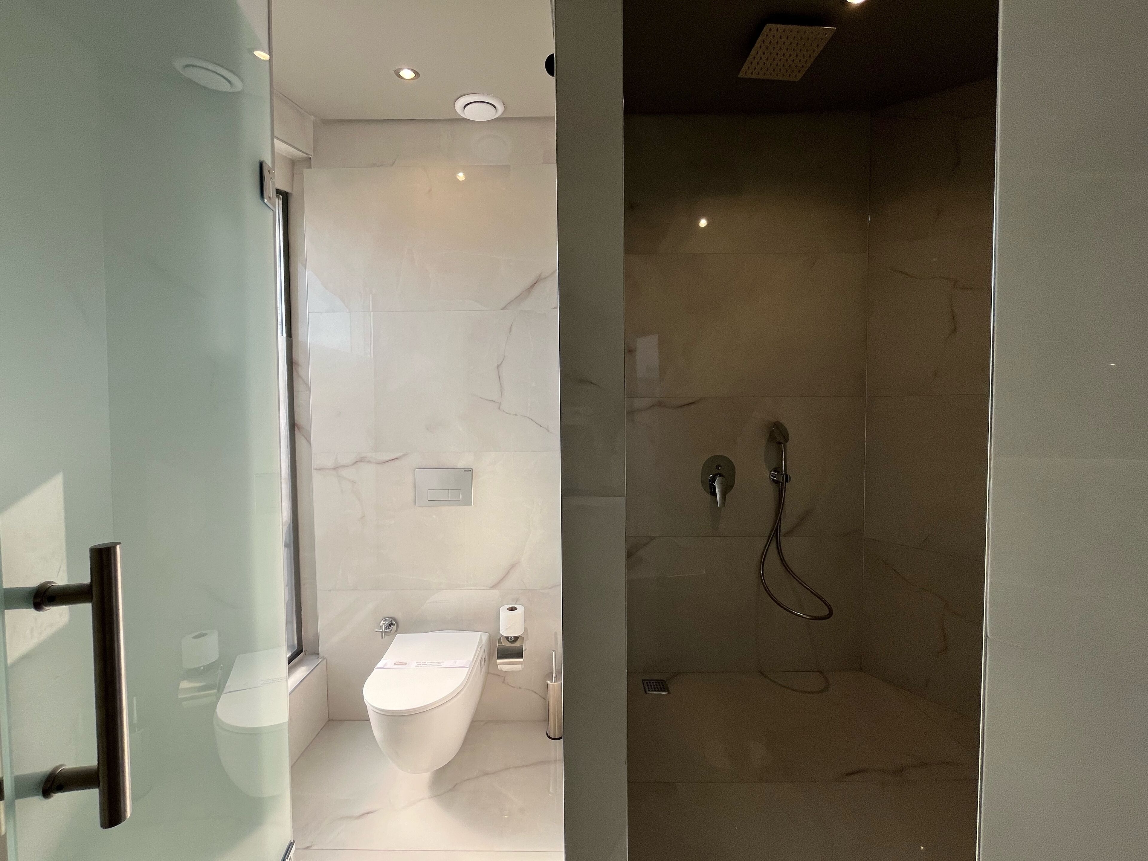 Une salle de bain moderne avec une douche à parois de verre, des toilettes et un lavabo.