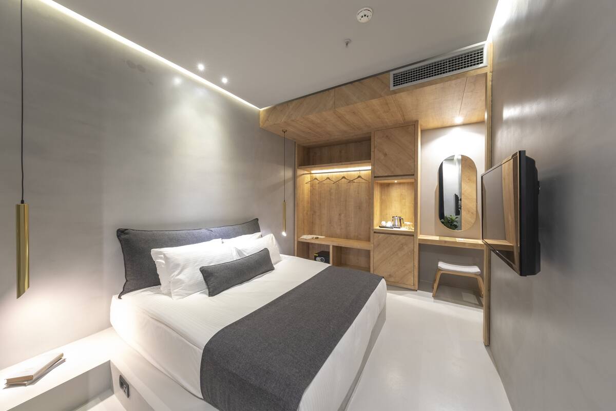 Ein modernes Schlafzimmer mit einem großen Bett, Nachttischen, einem Einbauschrank und einem an der Wand befestigten Fernseher.