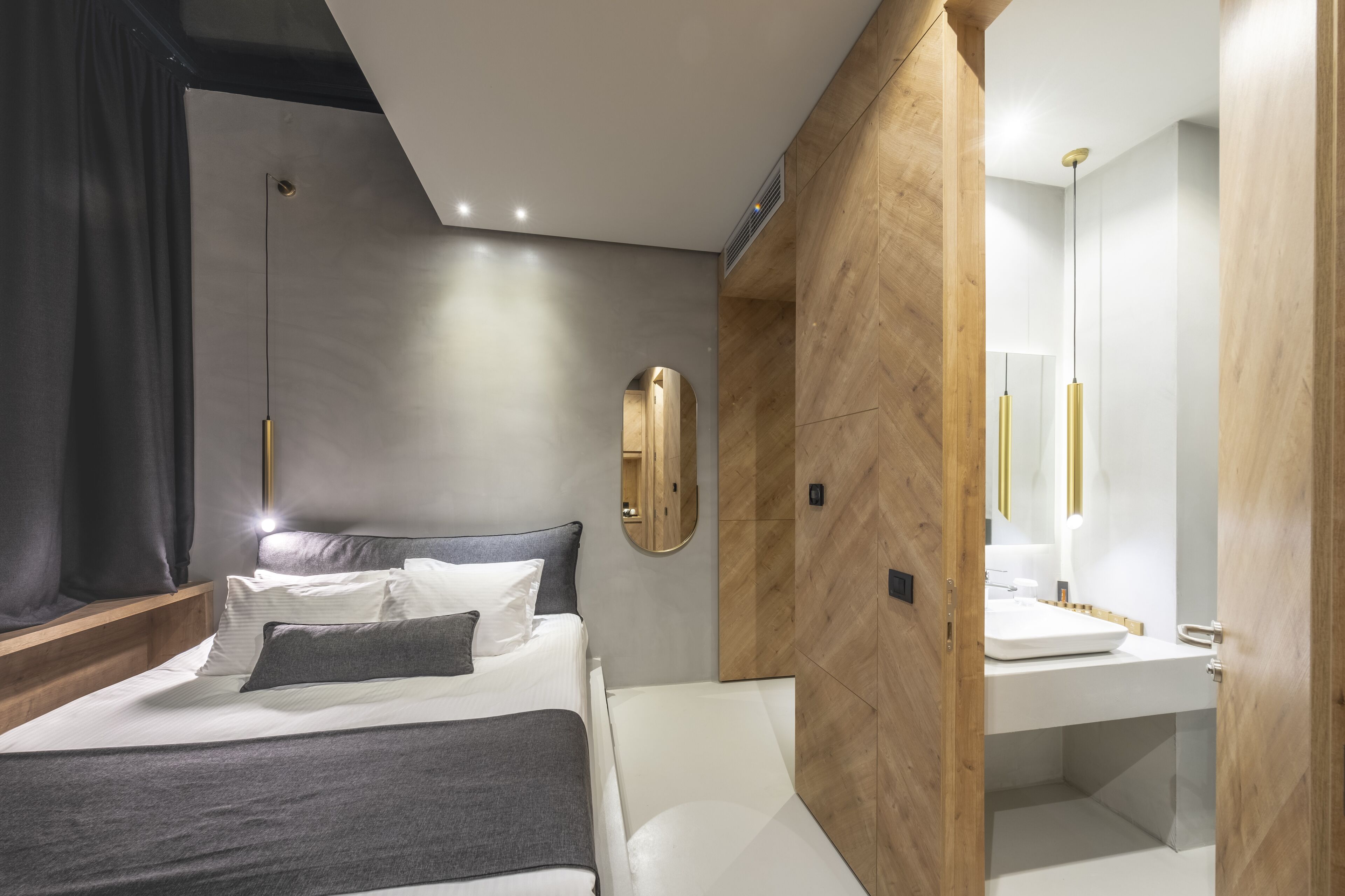 A modern hotel room with a bed, bedside table, and a wooden partition wall.