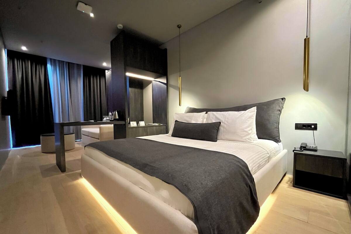 Ein modernes Hotelzimmer mit einem großen Bett, Nachttischen, einem Spiegel und einem Schreibtisch mit Stuhl.