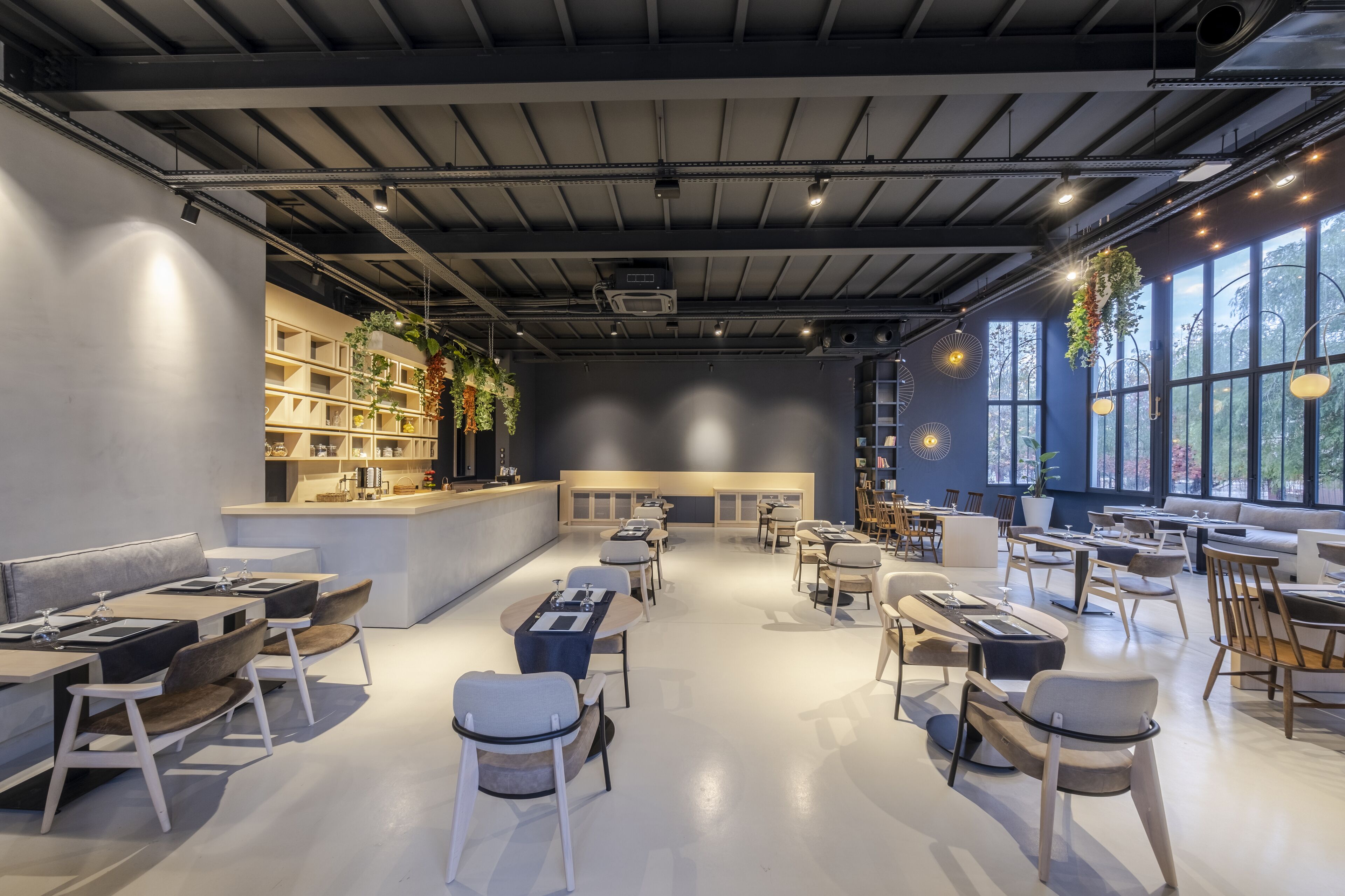 A modern restaurant with a bar area, seating arrangements, and large windows.