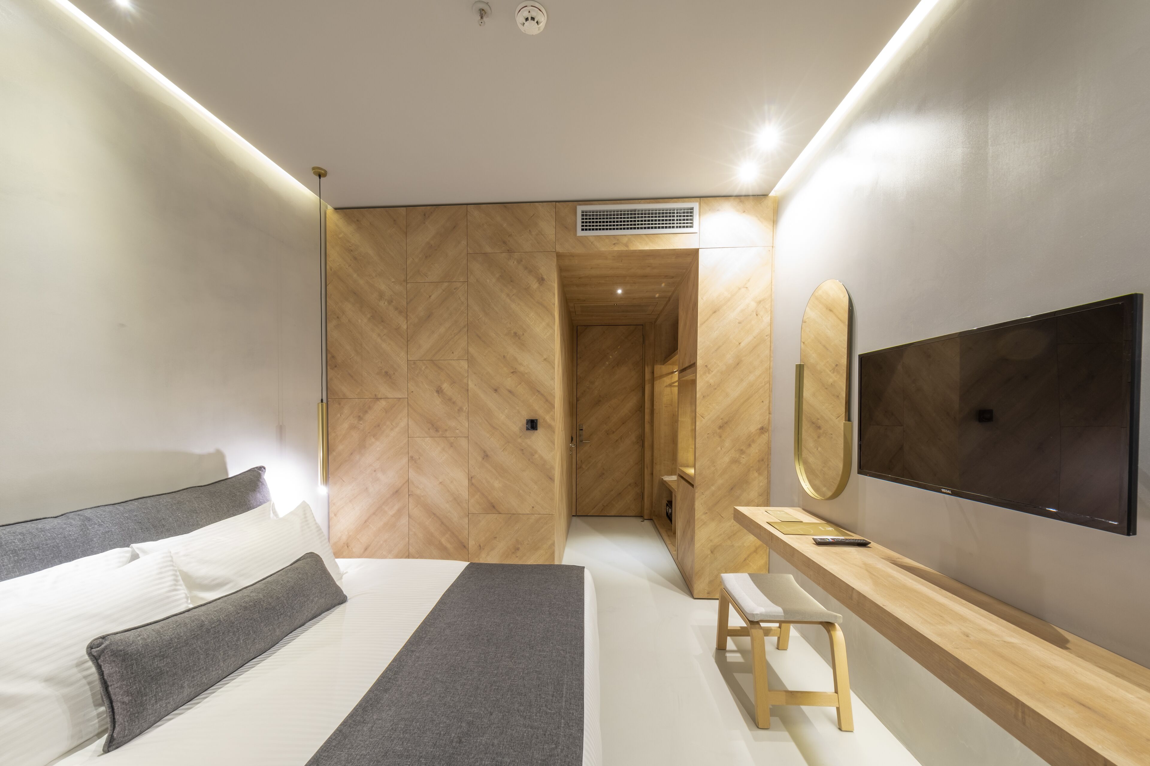 A modern bedroom with a bed, bedside table, and a TV mounted on the wall.